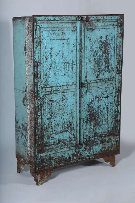 Industrial riveted cabinet in distressed blue patina. Dual locking mechanism, three shelves and two drawers inside. Three exterior handles.