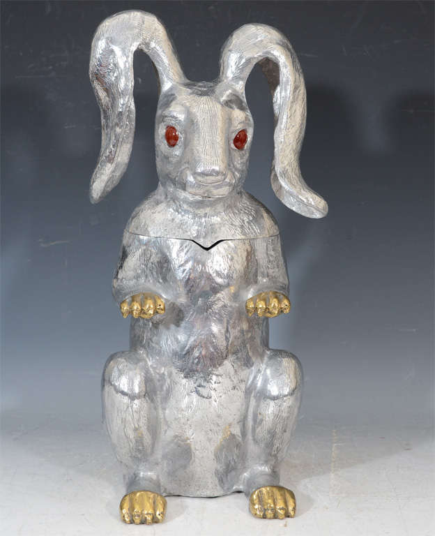 A champagne or wine bucket in the shape of a Rabbit. The piece is in cast aluminum with gold-tone paws and red carnelian eyes. The piece is signed and dated on the bottom.
