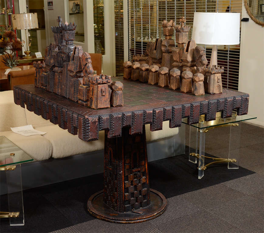 A large pedestal base game table with matching chess pieces. Both table and pieces have elaborately designed details. The pieces themselves come apart and have interior 