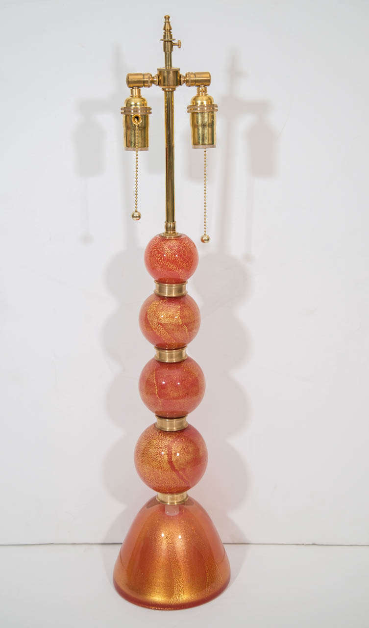 A striking pair of lamps in orange Murano glass with gold inclusions and brass spacers.  The lamps have been restored and re-wired.