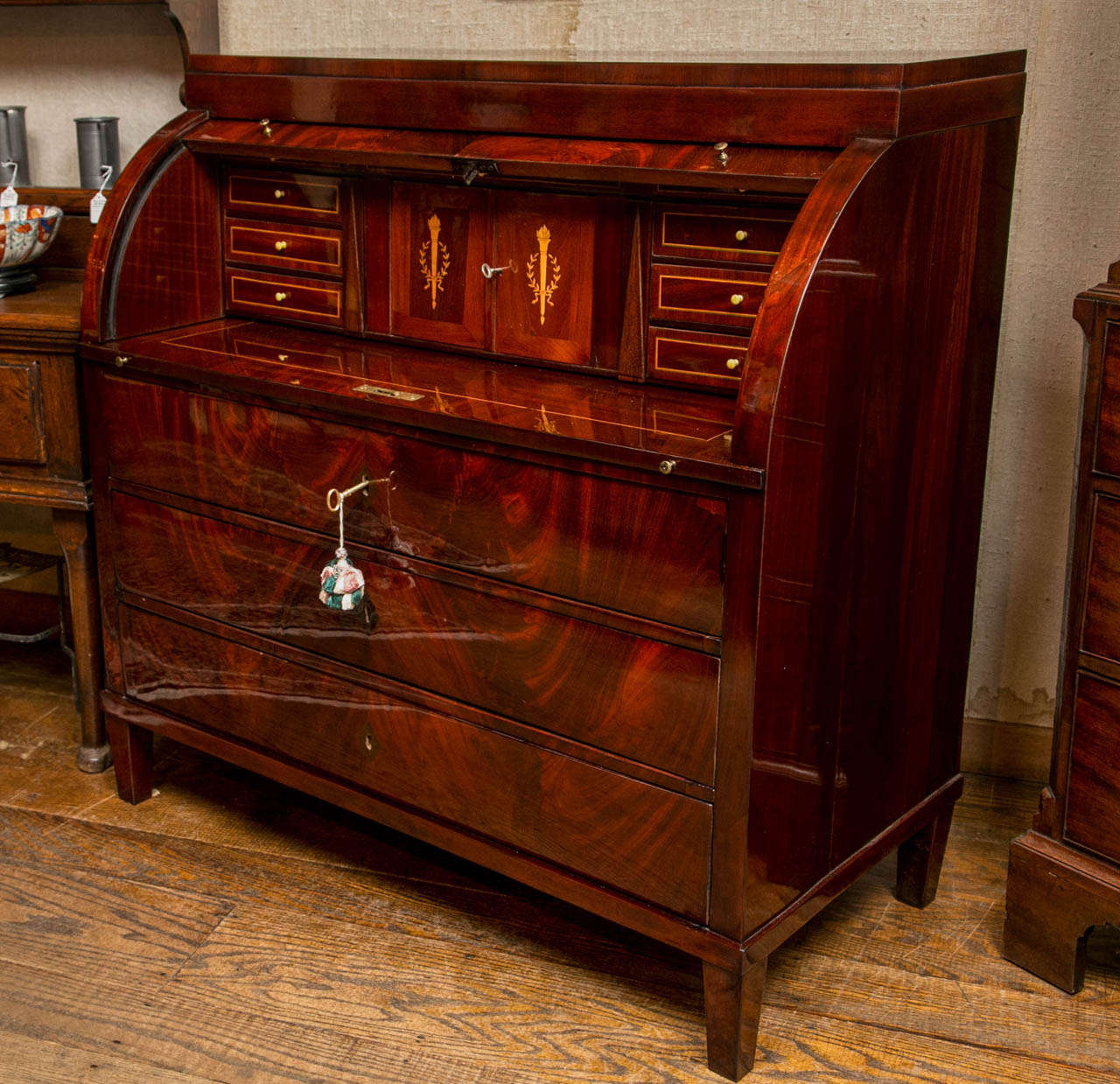 Swathed in a superb cut of flame mahogany veneer, this handsome cylinder desk, with its clean, near-Bedermeier lines would be a stunning addition to any well-appointed home. The bookmatched flame cascades down the entire front of this case down the