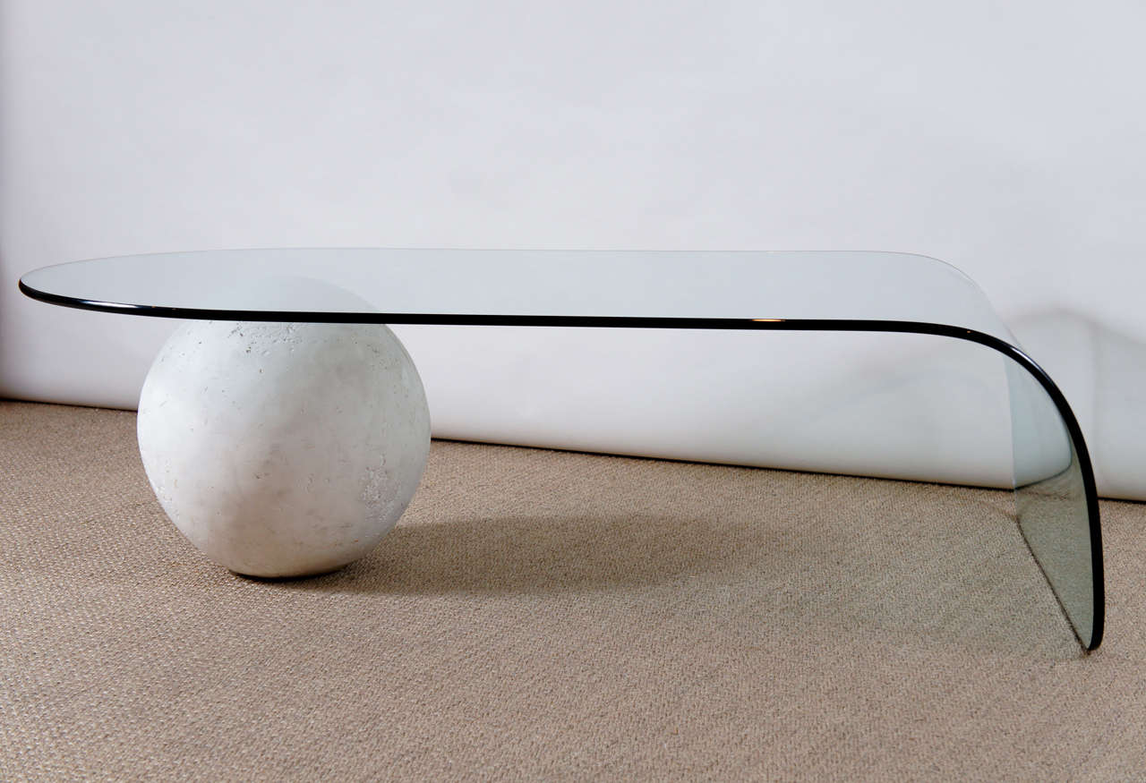 Here is an elegant and modern glass coffee table with a waterfall edge and a plaster ball base. The ball has a flat base for stability and can be positioned in various ways.