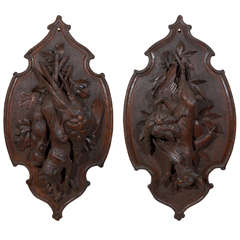 Pair of carved black forest hunting-themed wall plaques