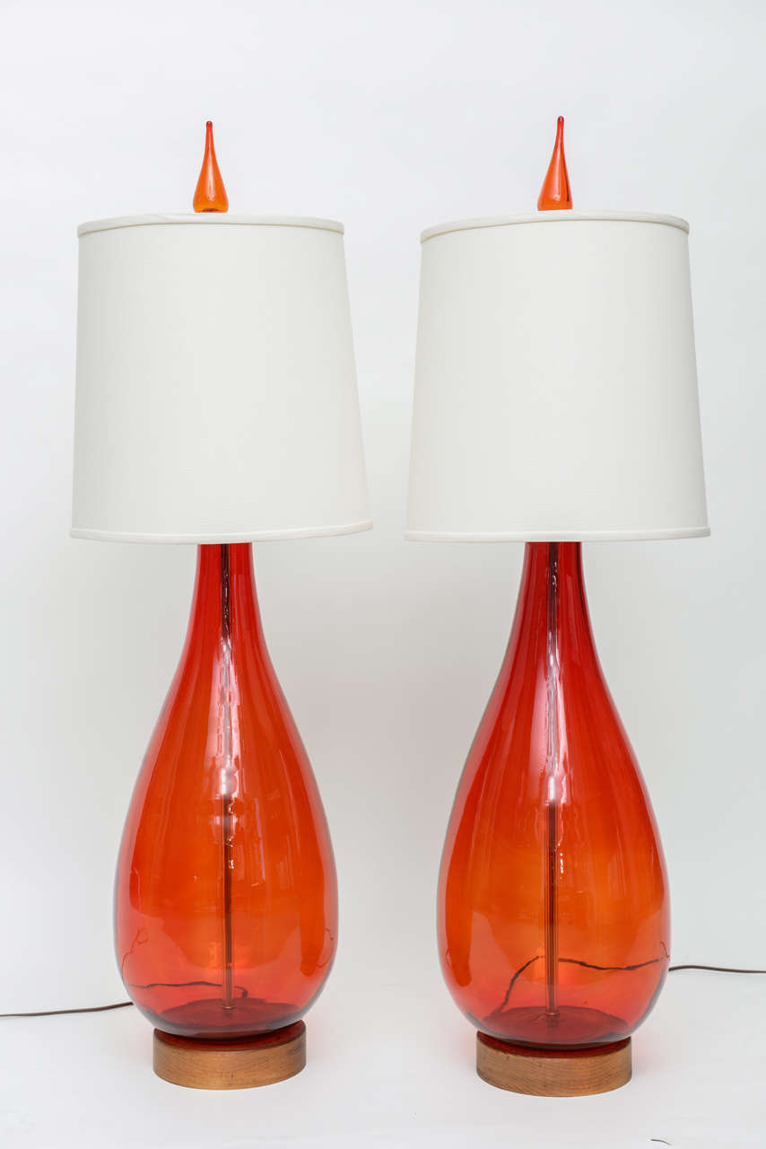 Gigantic pair of tangerine color glass lamps with original finials.