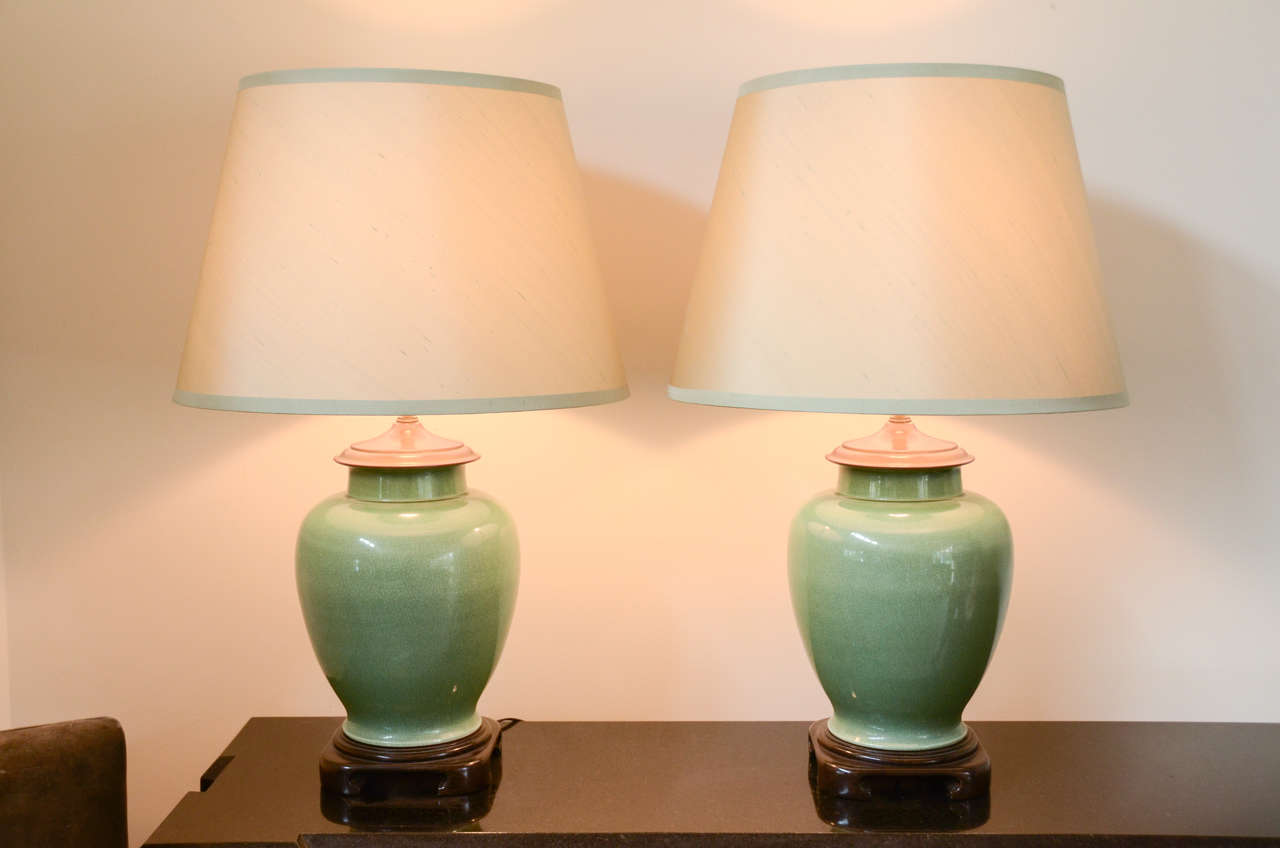 This beautiful pair of Jade color ginger jar lamps are mounted on Wooden asian style bases. The lamps have been newly rewired and have new fabric shades.
