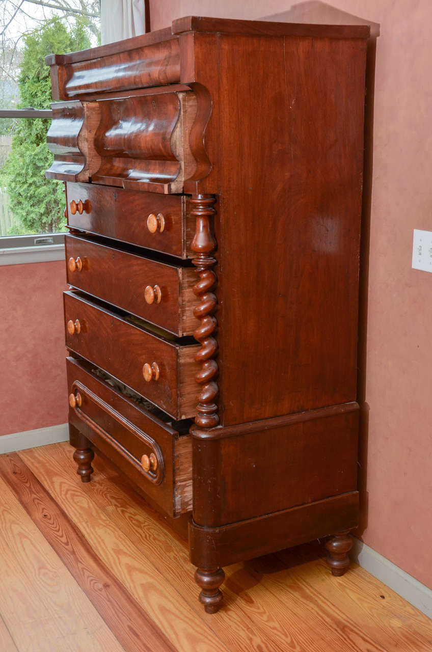 Large and impressive Scottish gentleman's clothing chest of drawers with spiral column decoration.  The casework is beautifully veneered with book matched drawer fronts in a rich dark red-brown mahogany.  At the top there is a shallow drawer, and