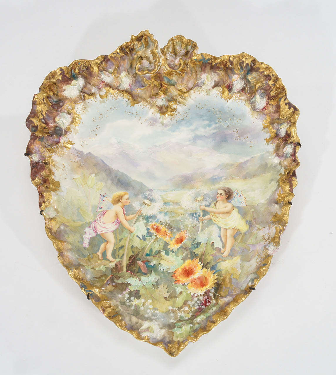 A rare and extraordinary large heart-shaped porcelain plaque is made by G. W. Turner, Tunstall, England dating from 1890s. The border is a work of art unto itself with a soft Impressionistic palette and the subject is both whimsical and Romantic.