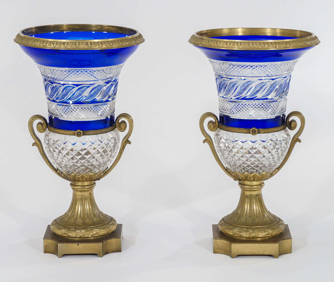 A pair of stunning 19th century Russian, cobalt cut to clear crystal mantel vases with Austrian bronze mounts. The bronze molded handles and elegant bases frame the amazing leaf and diamond point cut pattern in the crystal. These vases were