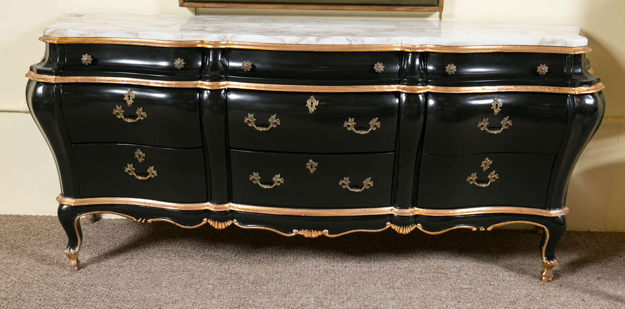 A bombe marble-top ebonized sideboard dresser. This Louis XV style bombe chest dresser can be used in almost any area of the home. The bombe sides and front of a lovely ebonized finish with clay and gilt gold design supporting a white marble top.