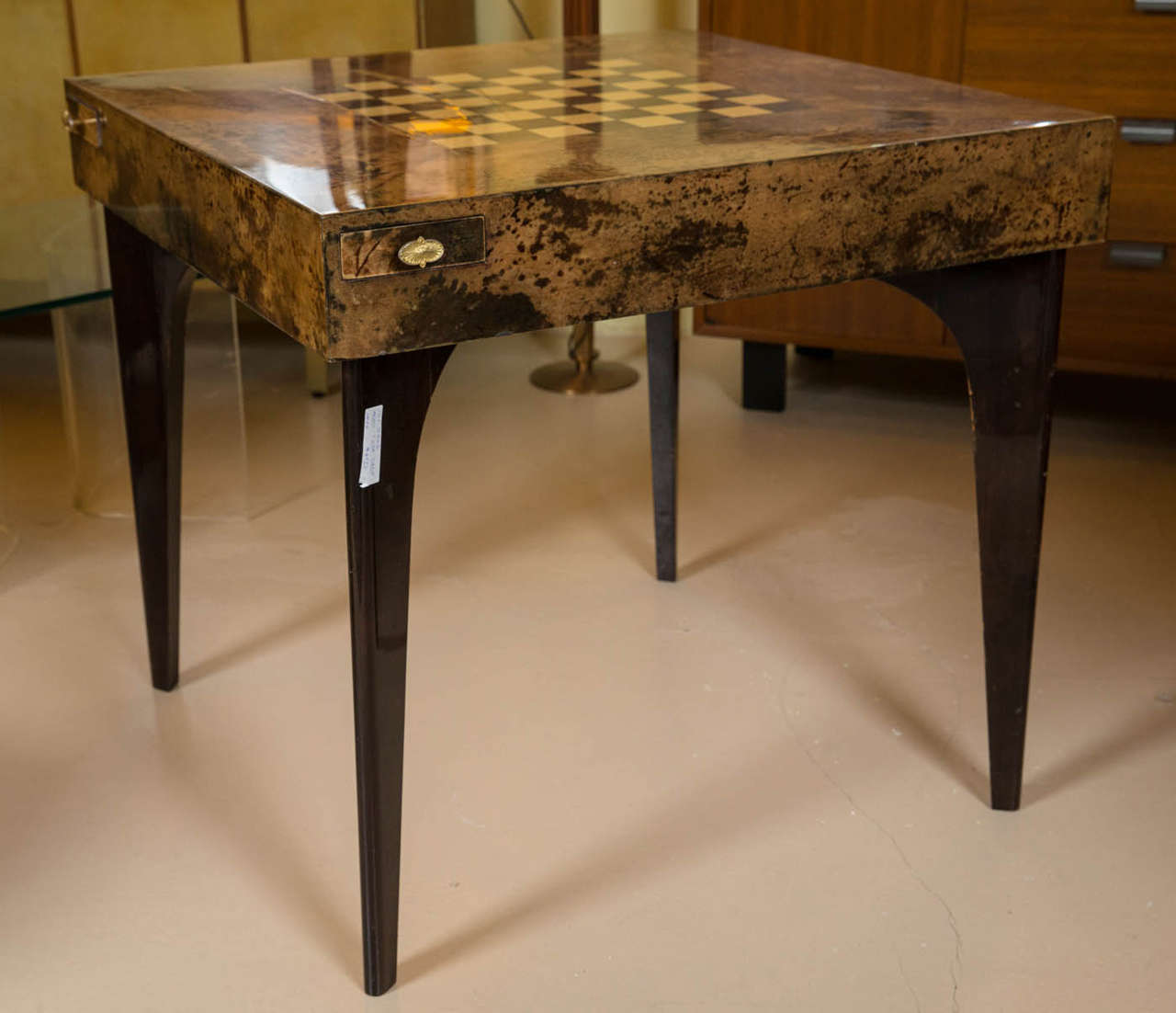 This wonderfully unique Aldo Tura game table with the top covered with goatskin parchment and inlaid chess board. The four legs of lacquer carrying a tortoiseshell square-shaped topadorned with four pulled out brass trays and a drawer. This piece is