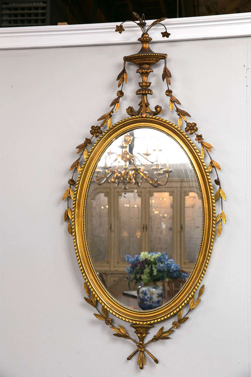 Carved Adams style mirror. Gloriously sized and wonderfully decorated floral bouquets abloom this beauty with flowing leaves and florets exquisitely draping the frame of this gilded mirror. Finely carved and detailed.