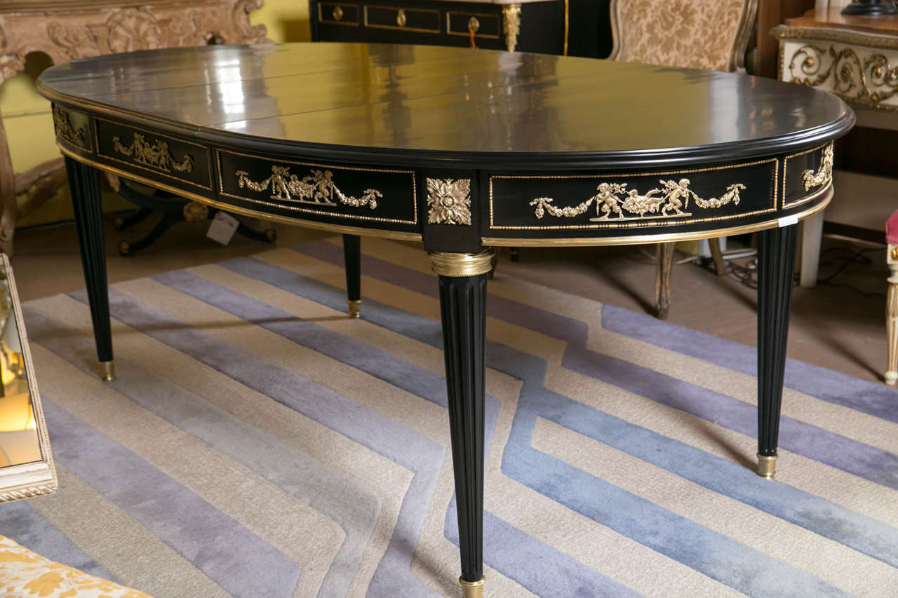 A fine French bronze-mounted Louis XVI style dining table by Maison Jansen. This wonderfully bronze-mounted dining table has one 20" leaf and is finely ebonized. The bronze sabots supporting a fluted tapering leg terminating in a circular