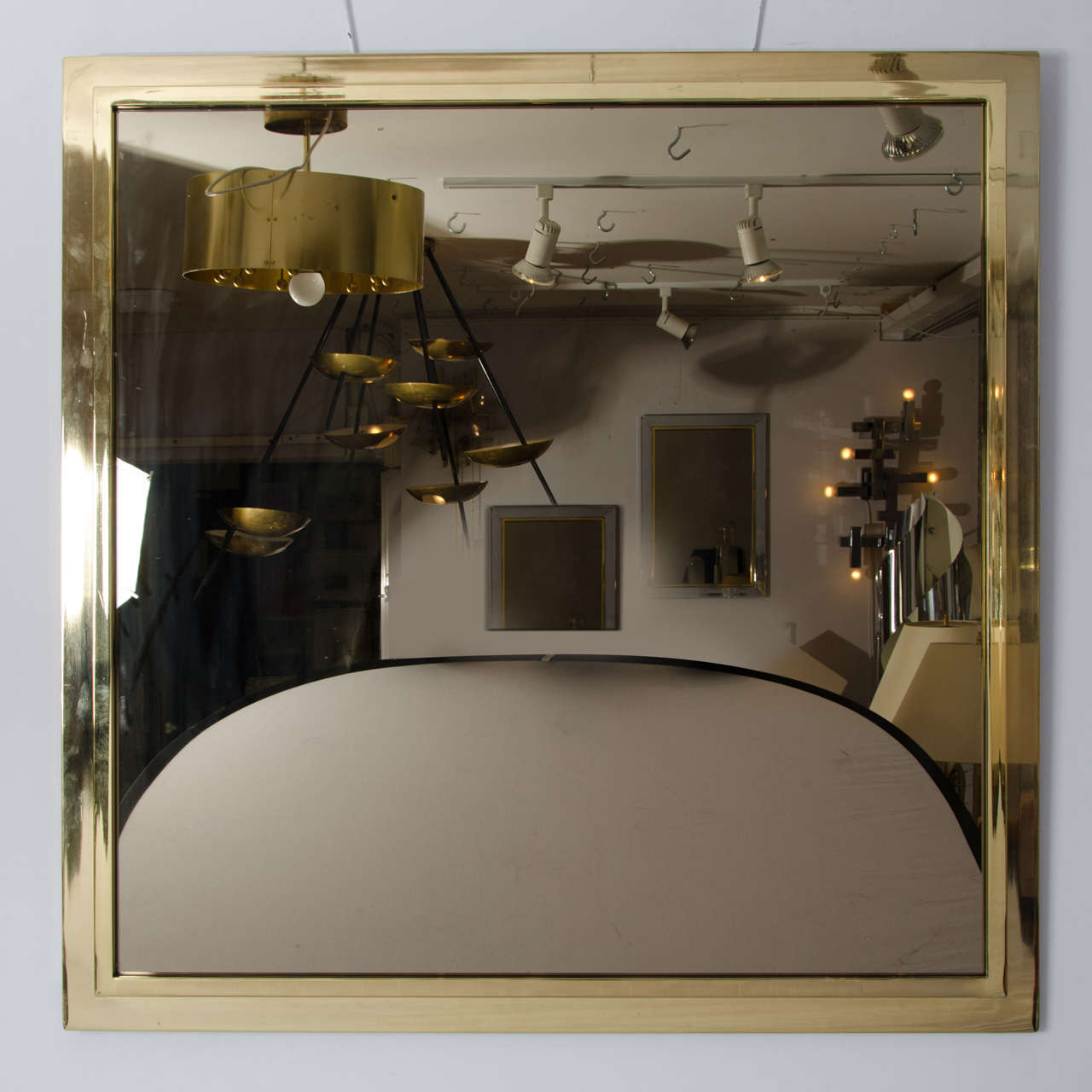 The gold-plated brass frame forms a double step enclosure around the bronze tinted mirror.