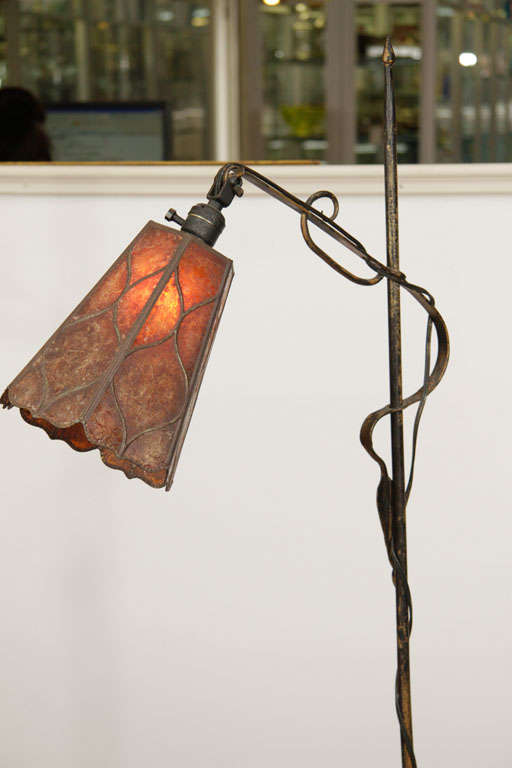 Standing lamp with tripod base, and articlated head with copper stained composite shade. The leaf and vine details on the base and the flower bulb shaped shade is meant to imitate a flower.