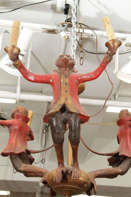 A wood chandelier consisting of three carved and painted monkeys, each holding two lights. The piece is originally from Grove Isle Hotel in Coconut Grove, Florida. There are four available.