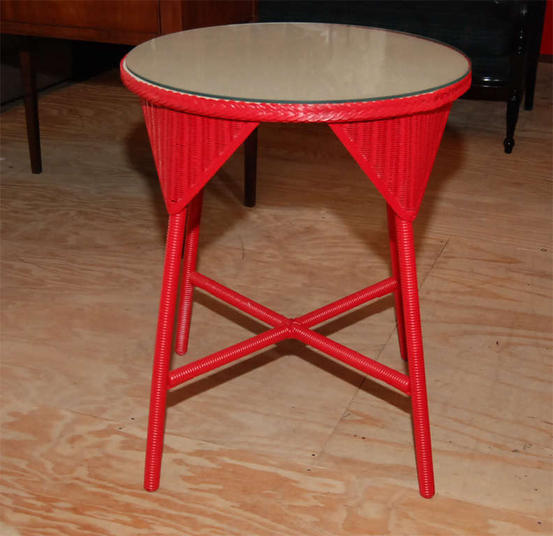 Red Lloyd Loom wicker table with linen top covered with glass