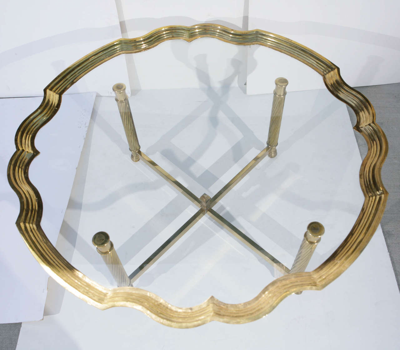 Brass edged glass piecrust coffee table on removable brass base with rams hoof in the style of Maison Charles