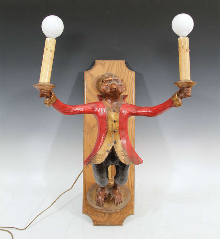 A pair of sconces consisting of a Monkey holding two lights. The pair is in carved and painted wood and originally from Grove Isle Hotel in Coconut Grove, Florida.