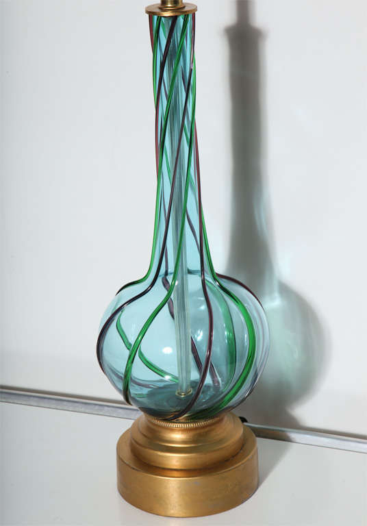 Statuesque Italian Murano Studio Marine Blue Glass Table Lamp, 1950's. Featuring n elongated gourd shape in hand blown translucent aqua Murano glass with applied Purple and Emerald ribbons on round step up bright Brass base with Brass neck. 