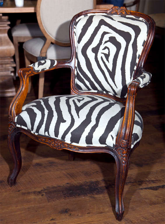 French walnut fauteuil in the rococo style, c. 1775, with carved flower motifs to the back crest, front rail and knees. Louis XV period, now covered in a zebra motif cotton.