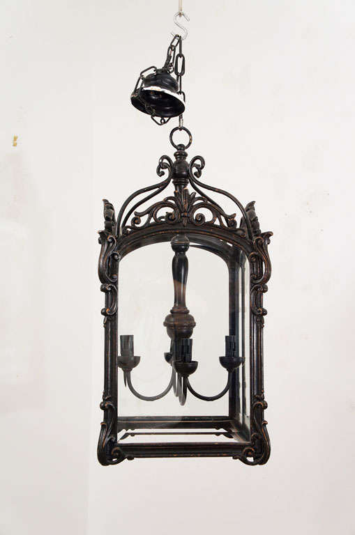 The outer box of this 4-light lantern is hand-carved ebonized wood with beveled glass panels. The top braces and the center pendant are hand-cast metal. The design is an early 20th Century copy of a mid-18th century Scandinavian adaptation of the
