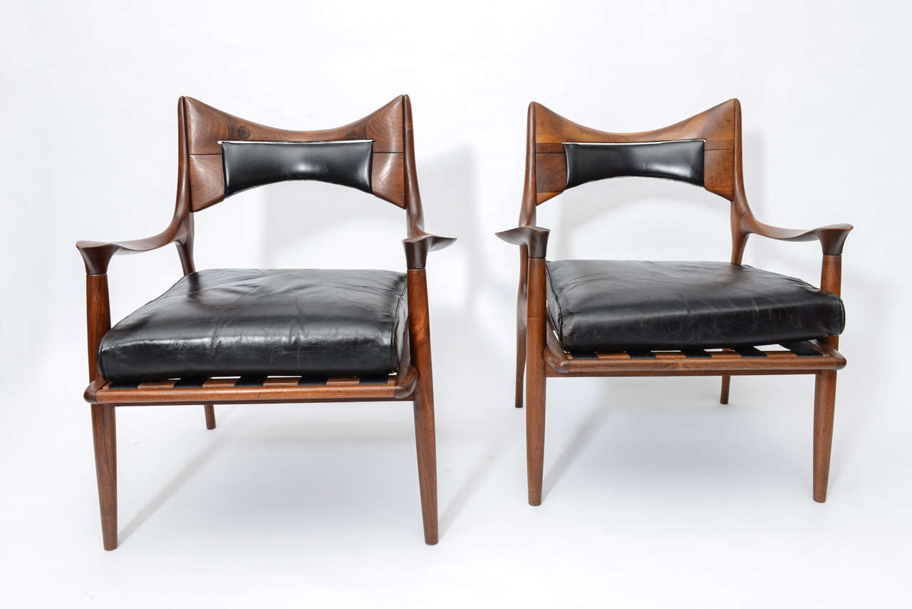 A rare pair of lounge chairs by Phillip Powell.
Expressive carved walnut frames retaining their original 
leather cushions.
Very few of these were made.