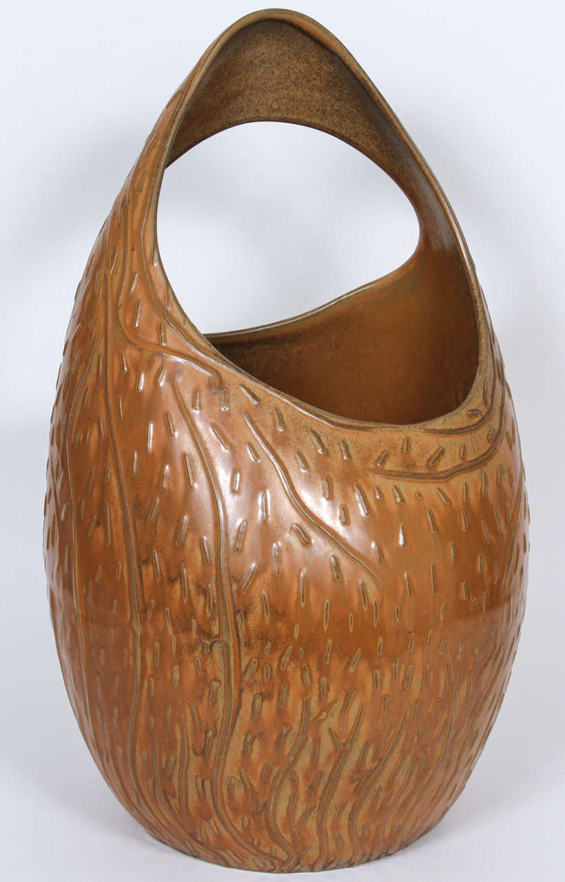 A huge ceramic vase or umbrella stand with two asymmetrical openings, and an all-over biomorphic pattern of raised veins and welts, covered in an earthy, semi-matte glaze.