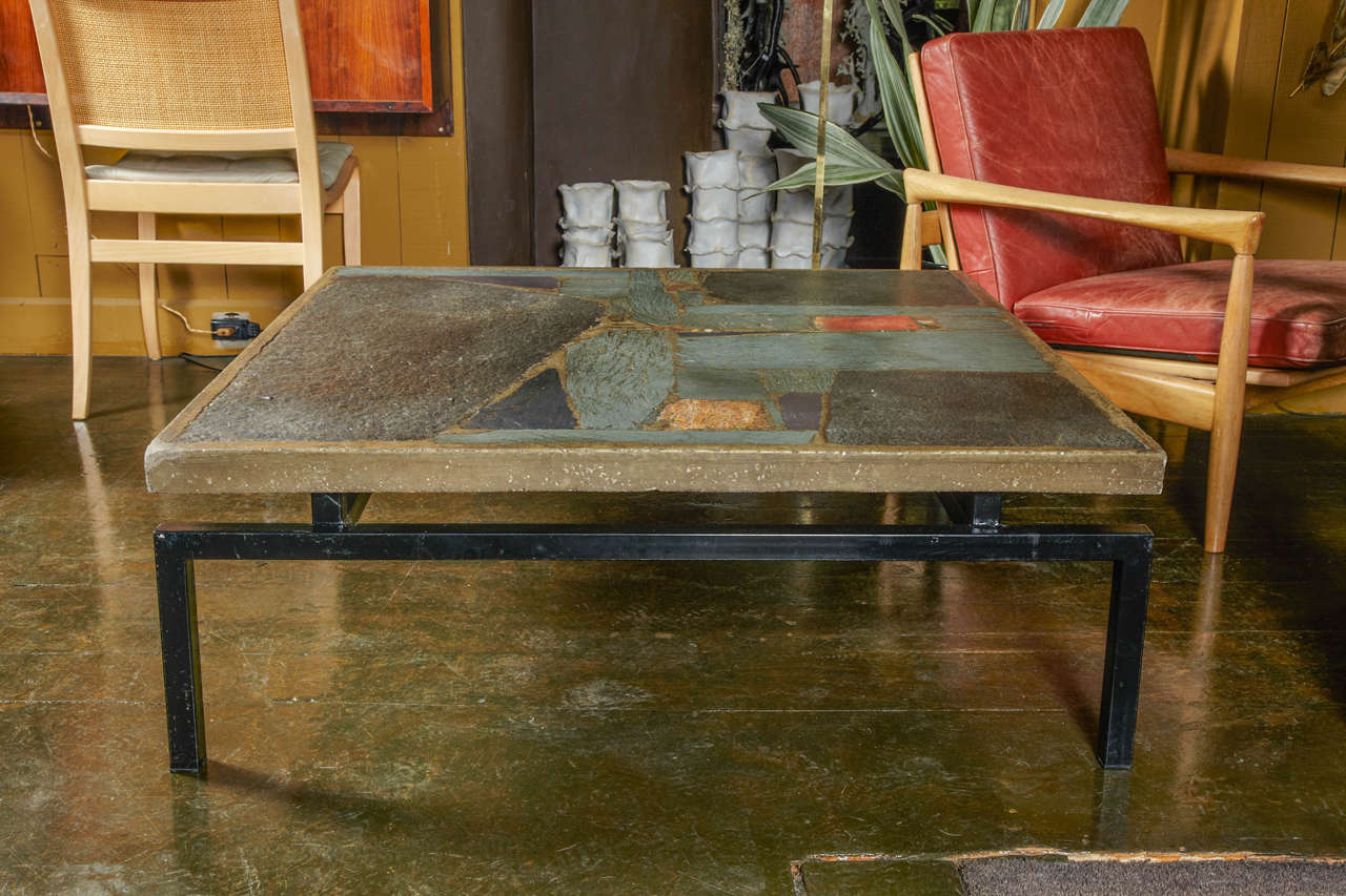 A modernist square cocktail table with a cement top incrustated with pieces of slate and stones elements and a black metal stem.
The table is signed by the Dutch artist Paul Kingma on a brass label and dated under the top circa 1989.