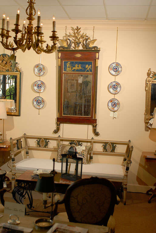 An Italian mirror with  gilt, polychrome and faux wood finish, sphinxes flanking the top of the mirror, eglomise panel above mirror and paw feet below. 


