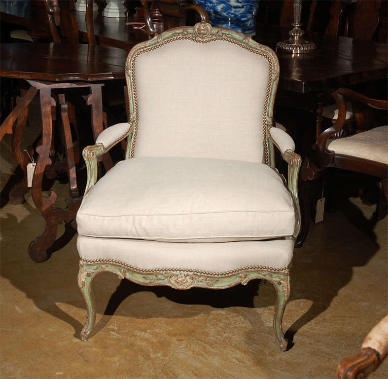 Hand-painted and carved, 19th century, French armchair with rose medallions and original brass studs. Upholstered in linen.