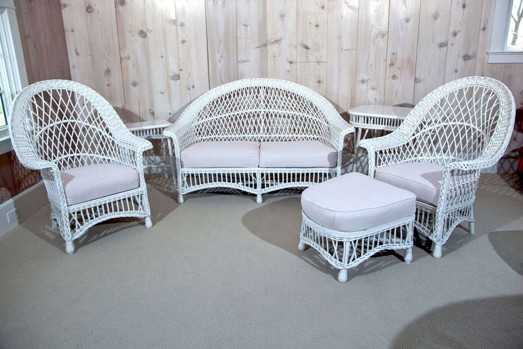 Four-piece antique bar harbor wicker porch set comprised of settee, two arm chairs, and one ottoman. Drop in spring cushions on seats and ottoman. Tables pictured are not included.

Dimensions:
Sofa 57.5