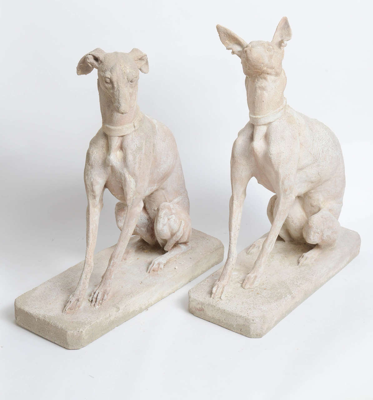 Exceptionally executed pair of limestone dogs (whippets) on bases.