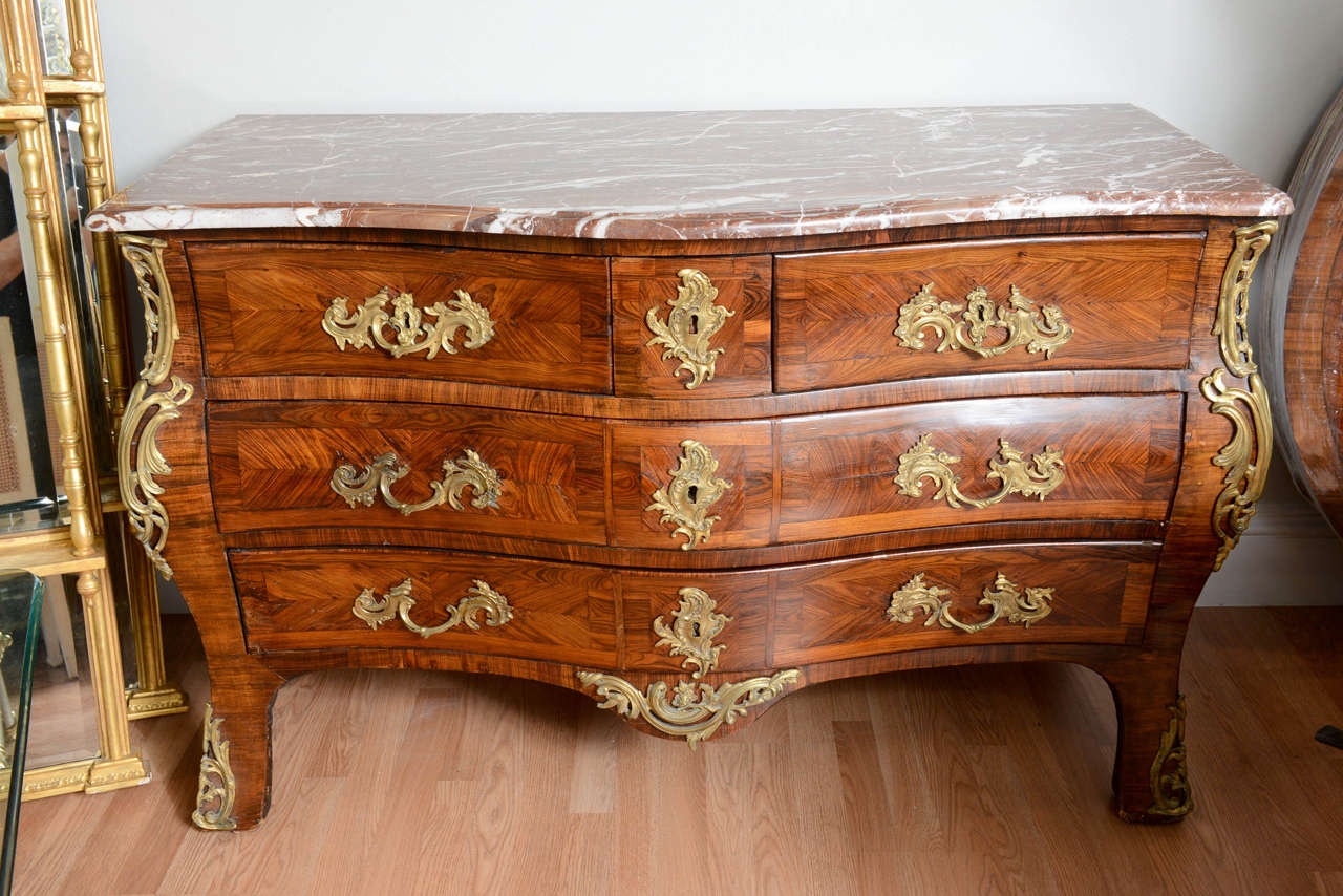 Outstanding example of 18th century Louis XV commode with beautiful marquetry work and exquisite marble top. This commode features five separate drawers with bronze ormolu mounts.
