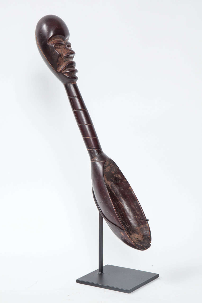 A decorative spoon with mask at the end of handle in the style of that from the Dan tribe of the Ivory coast and Liberia. This very provocative utensil becomes a wonderful piece of decorative art in its present form.