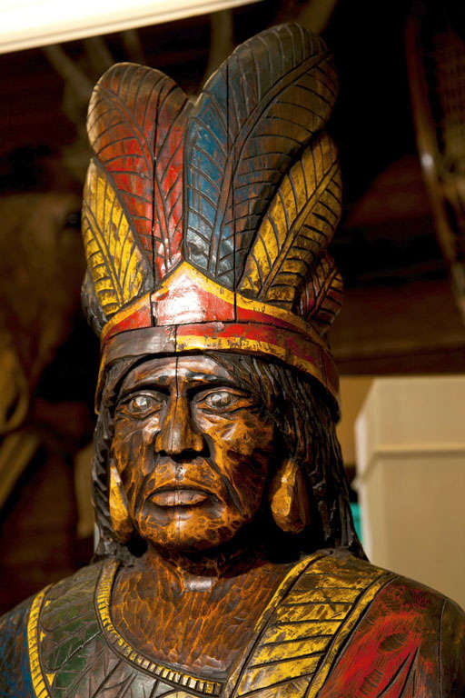 brightly painted wood Indian figure standing on platform.  Detailed carving of Native Dress.