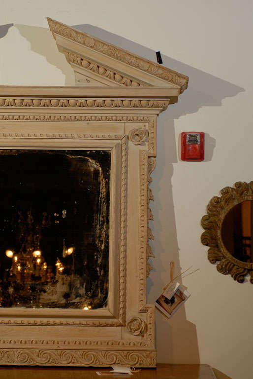 A large English Georgian style mirror from the early 20th century, with broken pediment, carved motifs and whitewashed finish. Created in England during the early years of the 20th century, this large mirror attracts our attention with its striking