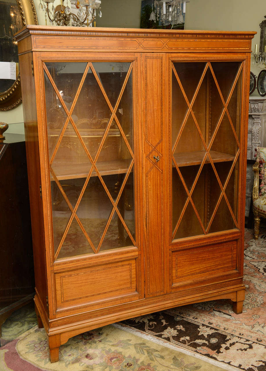 This is a superb satinwood bookcase.
To the front it has rosewood string inlay, and sits on square tapered legs. There are two doors and two shelves inside which are adjustable.
It's the original finish!