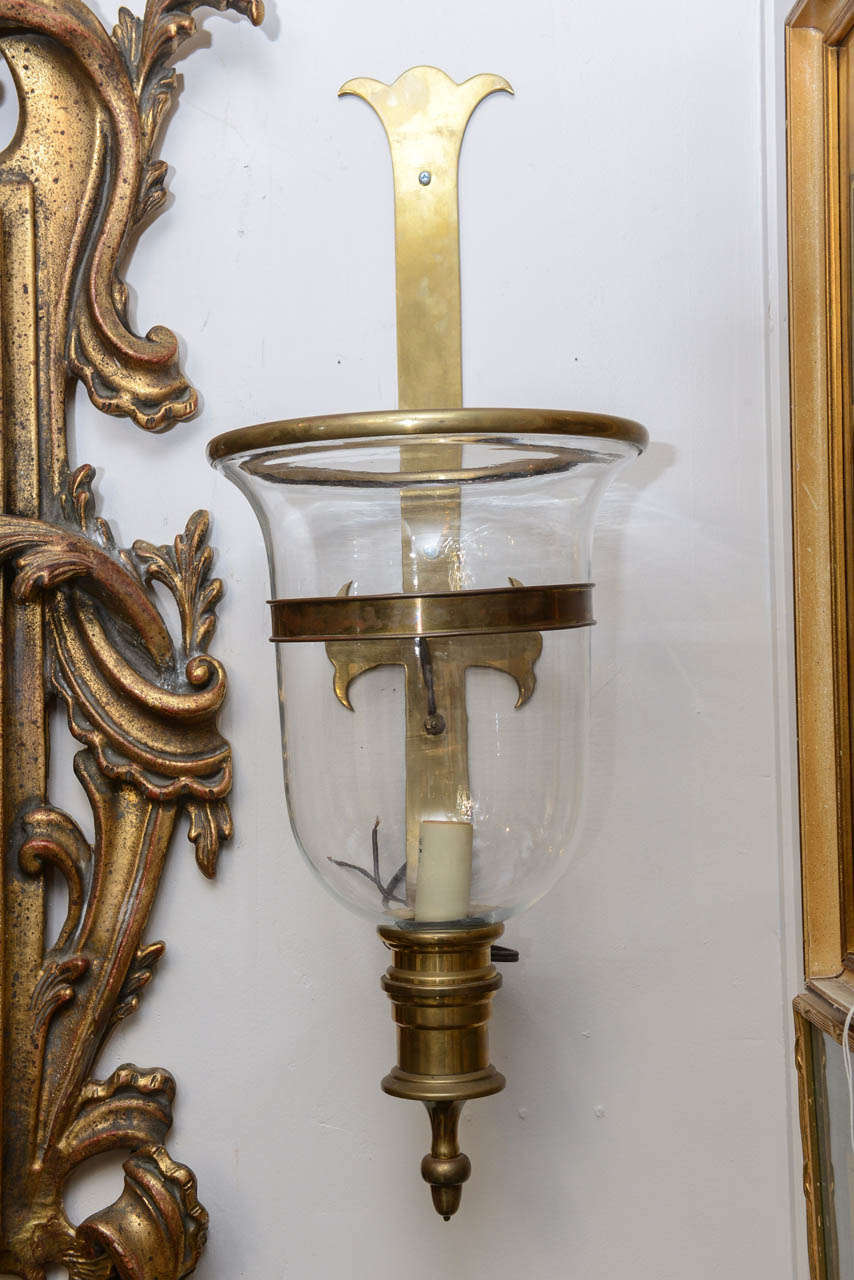 Pair of brass framed and glass hurricane sconces with beautiful patina.