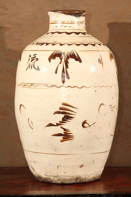Chinese Tz’u-chou Type Ceramic Wine Jar of ovoid form with narrow cylindrical neck. The buff stoneware body covered with white slip and transparent glaze and painted underglaze decoration in black pigment. Pots such as these were produced during the