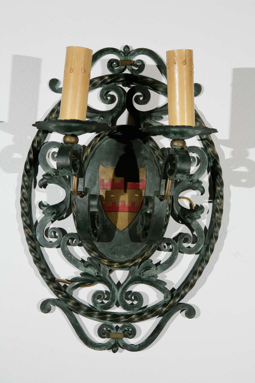 Pair of French double arm cast iron sconces with heraldic imagery.