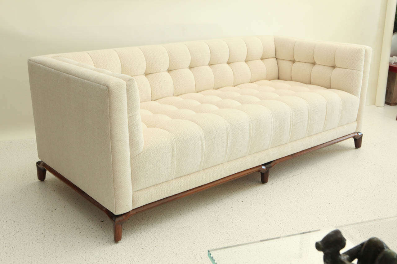 A chic biscuit-tufted sofa by Monteverdi Young, newly upholstered in a cream chenille fabric shot through with gold Lurex, and set on stylish wood base.