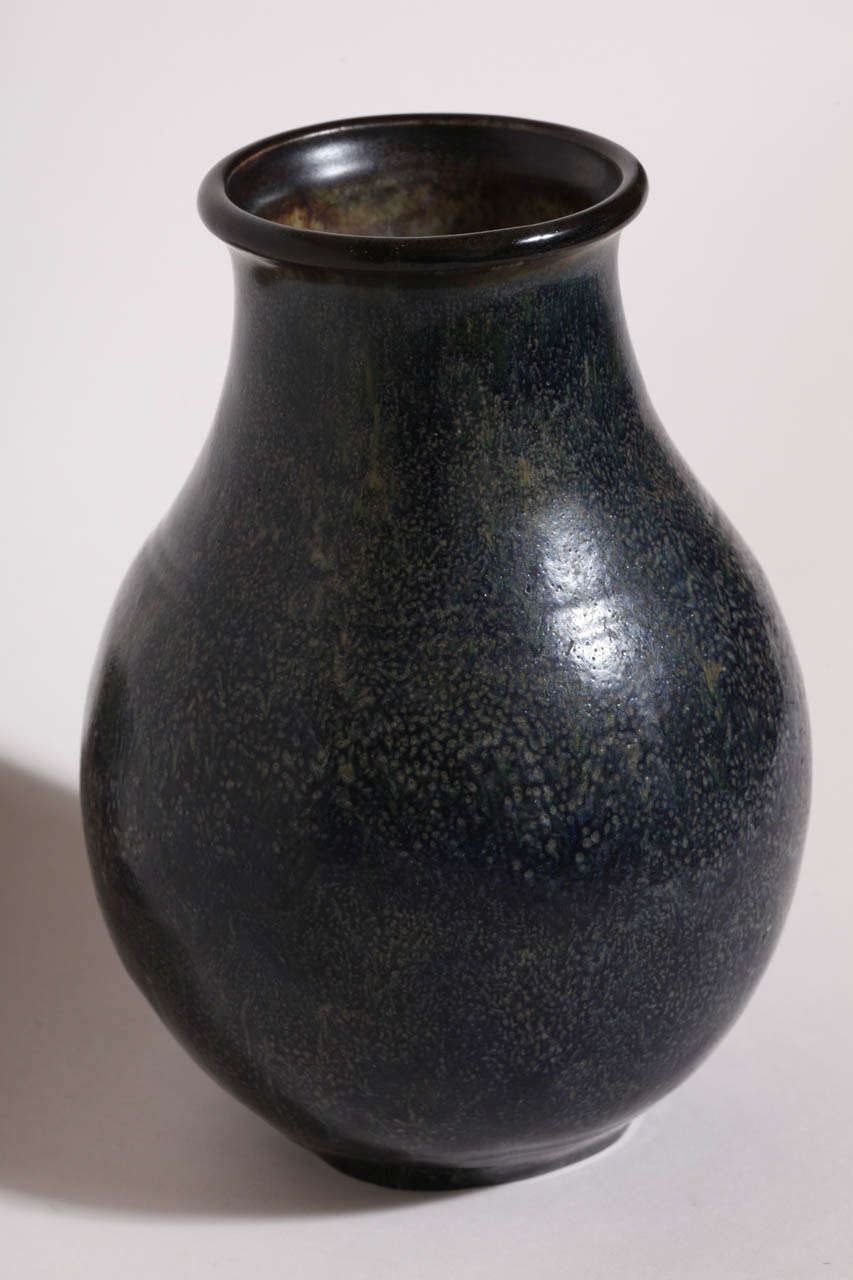 This stoneware vase is a mottled blue with two indented bands around the neck and a dark brown rim.
Signed: EDecoeur incised

Orphaned as a child, Decoeur served as an apprentice to Edmond Lachenal between 1889-1902 before becoming a master