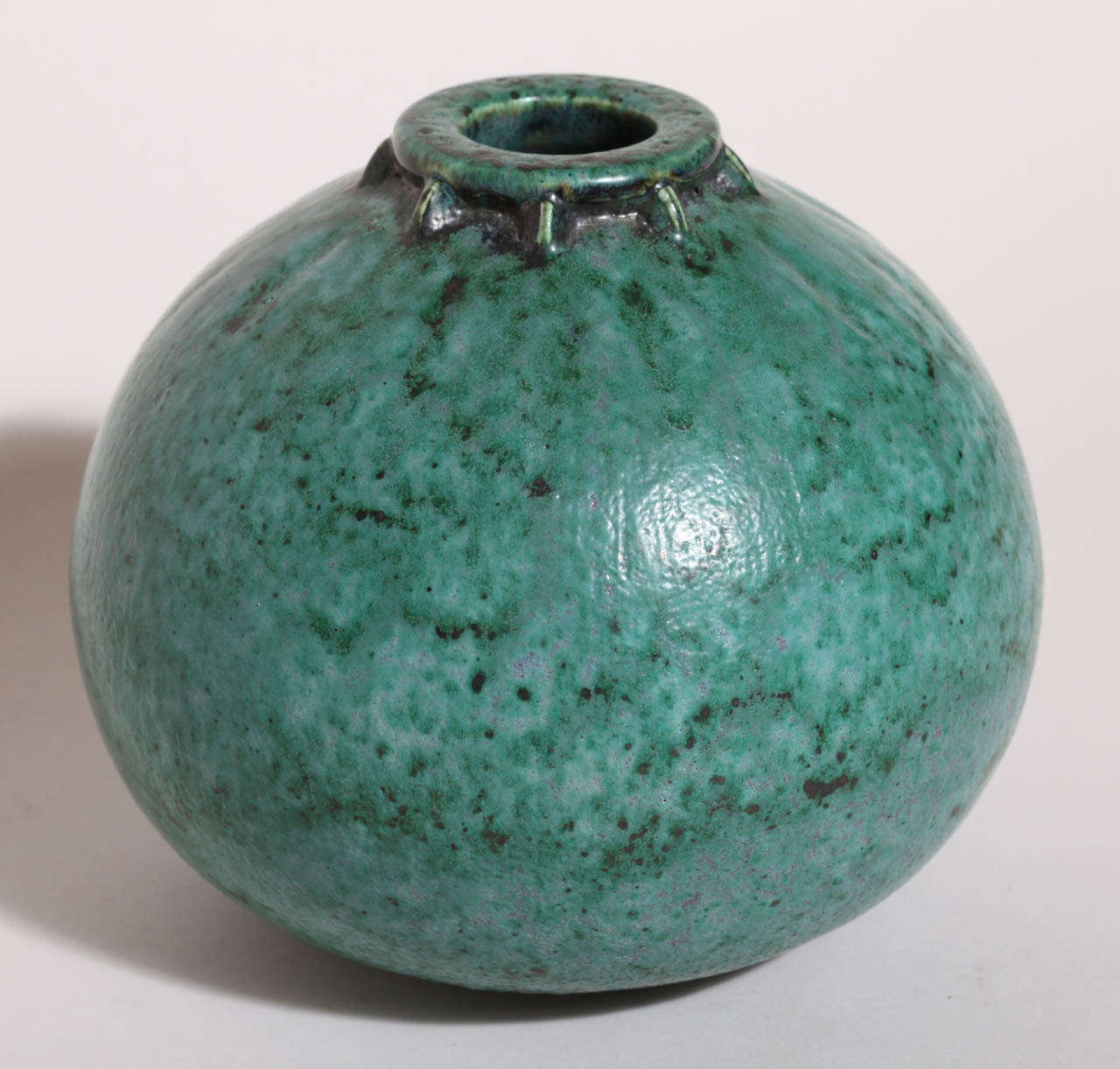 This spherical stoneware vase has a turquoise glaze with purple undertones, vertical indentions below the collar and vertical struts around the collar.
Signed: ED incised

Orphaned as a child, Decoeur served as an apprentice to Edmond Lachenal