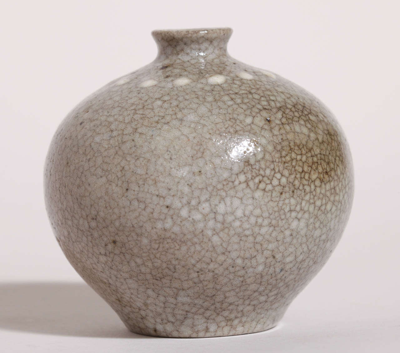 Spherical stoneware vase on a small foot with a flared neck in craquelure gray celadon and with white enamel beads around the body superiorly.
Signed: 