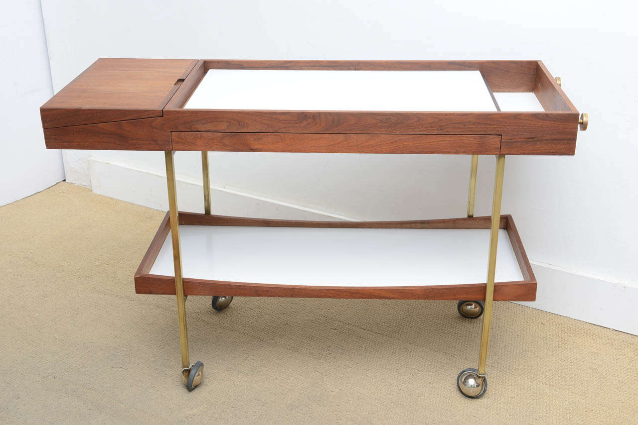 Super sleek cool MIDCENTURY modern Bar Kart dating back to the sixties . This sleek modern bar Kart was designed by Paul McCobb in the 1960,s  is Made of Teak , Brass and Glass  . It extends , pulls out , Rolls very practical and functional . A