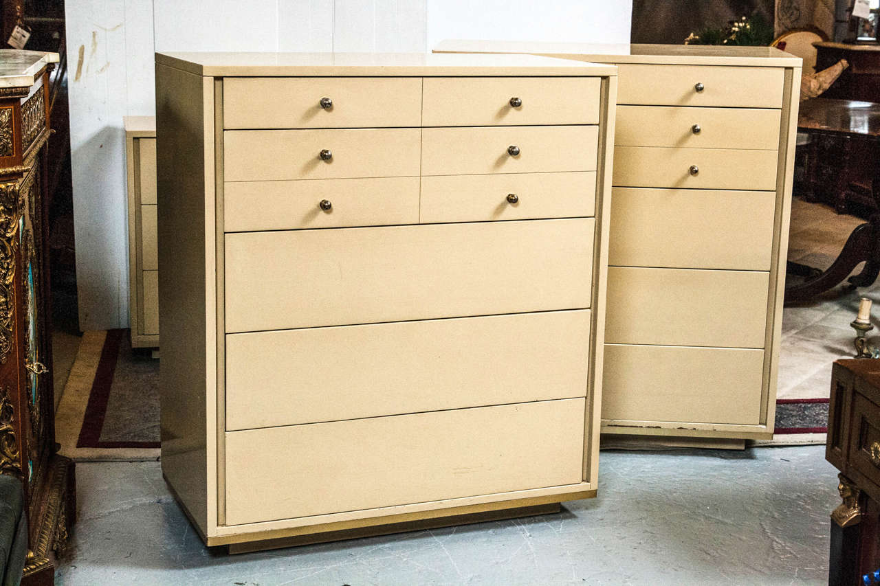 Pair of John Stuart chest on chests. A stunning and unique pair of chests with five drawers beige lacquer. The top two drawers have silver plated pulls, giving a modern aesthetic. This is a well-made main stream modern pair of chests. Labeled John