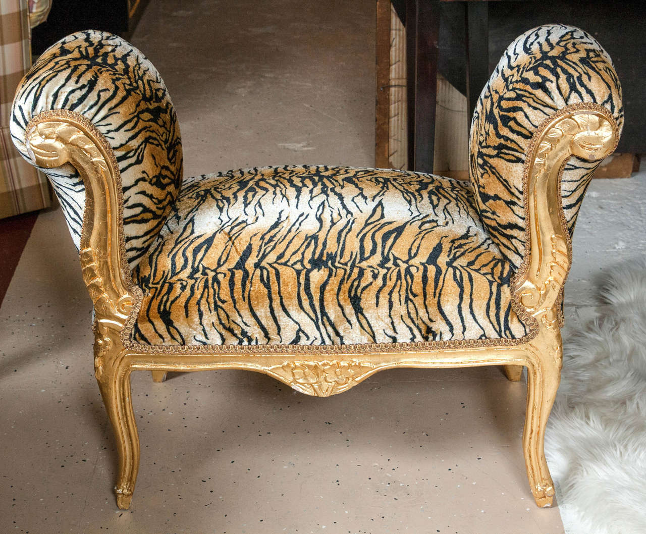 Chanel style faux tiger furred gilt bench. Exotic and fun this is sure to inspire conversation. The gilt wood has carved scrolled detailed frames with a magnificent floral bouquet on the apron. Energetic and vibrant fabric - Great for a vanity bench