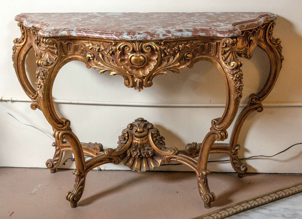 Marble-top Louis XV style console table by Jansen. This is a fine and early example of French design at its best. This Louis XV style console has a deep serpentine design leg with a lower support under-carriage displaying a shell design with flowing