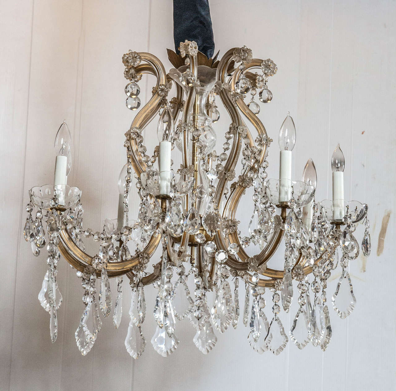 Hollywood Regency eight-light crystal chandelier. Exquisite and dainty S-shaped arms with shimmering crystals that reflect light for old world charm. Beautiful florets decorate the glass arms and sparkling crystals galore. This wonderful piece adds