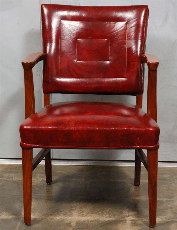 This handsome pair of armchairs with red leather upholstery have nicely shaped armrests, tapered legs and supporting stretchers. Originally used at a banker's desk, this pair is well suited to a variety of settings. 
